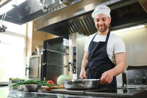 Chef cook in uniform cooking in the big cooker at the restaurant kitchen photo