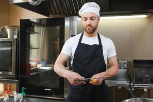 Chef cook in uniform cooking in the big cooker at the restaurant kitchen photo