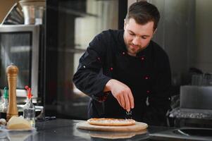 chef baker in uniform making pizza at kitchen photo