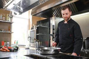 Chef cook in uniform cooking in the big cooker at the restaurant kitchen photo