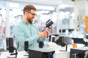 A man chooses a professional microphone to record a blog. Electronics store photo