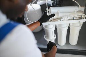Technician installing reverse osmosis equipment under the sink photo