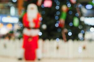 Blurred Santa Claus near the tree in the lobby of shopping center photo