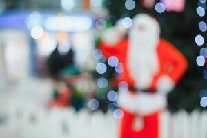 Blurred Santa Claus near the tree in the lobby of shopping center photo
