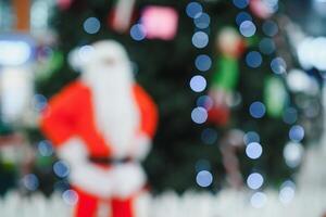 Blurred Santa Claus near the tree in the lobby of shopping center photo