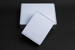 Two boxes sitting on top of each other one slightly smaller than the other The smaller one is on top of the larger one with the long side of the smaller box photo