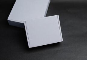 Two white boxes lying flat on a surface The smaller box is on top of the larger box The larger box is slightly offset to the left photo