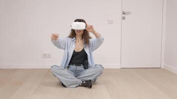 Young woman in VR glasses using modern technology creating room design, moving hands in air, standing in new apartment during renovation. Virtual reality and repair concept video