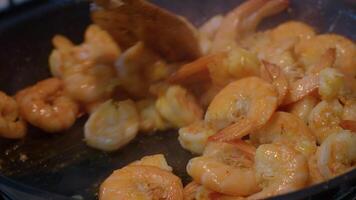 Close up shot of shrimps being fried in pan with butter stirred by a spatula.. video