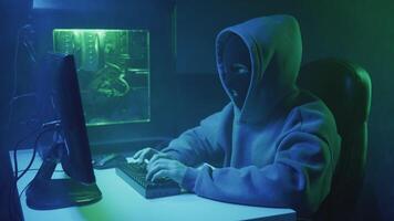 Cybercriminal hacker in black mask typing on keyboard video
