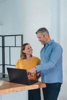 Man and woman smiling professional business people talking using laptop computer working in office. photo