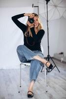 Portrait of a female photographer in a studio setting, holding a camera and looking focused. A perfect shot for showcasing the art of photography. photo