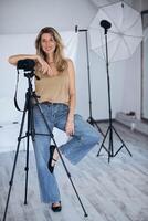 The photo shows a female photographer working in a studio environment.