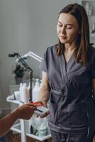 Cosmetologist processes a contactless payment from a client using a card reader photo