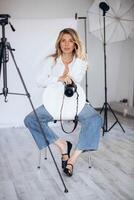 Female photographer in a modern studio, confidently holding a camera. The lighting and composition create a strong image of creative empowerment. photo