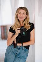 A photographer standing in a well-lit studio, holding a camera and preparing for a shoot. The photo emphasizes professionalism and a passion for photography.