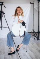 Female photographer in a modern studio, confidently holding a camera. The lighting and composition create a strong image of creative empowerment. photo