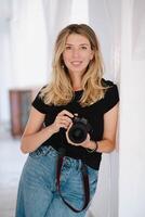 Female photographer holding a camera, standing confidently in a modern studio. A dynamic scene highlighting passion and creativity in photography. photo