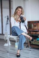 The photo shows a female photographer working in a studio environment. She is surrounded by professional equipment, focusing on capturing the perfect shot in a creative and controlled setting