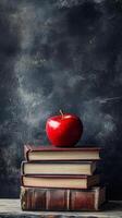 A fresh red apple placed atop a stack of vintage books on a wooden table in a cozy setting photo