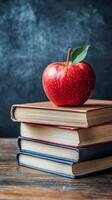 A fresh red apple placed atop a stack of vintage books on a wooden table in a cozy setting photo