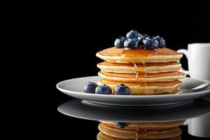 Delicious stack of pancakes with berries and a cup of coffee on a reflective surface photo