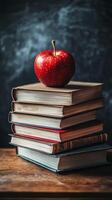 A fresh red apple placed atop a stack of vintage books on a wooden table in a cozy setting photo