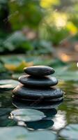 Four smooth stones stacked in serene water surrounded by lush greenery in a tranquil setting photo
