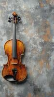A beautifully crafted wooden violin rests against a textured gray background photo