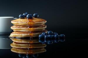 Delicious stack of pancakes with berries and a cup of coffee on a reflective surface photo