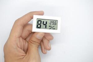 holding a humidity measuring thermometer, small size, portable, on a white background. photo