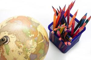 Selective focus, Top view globe with crayon or colored pencils in box on white background. Learning study and education concept. photo