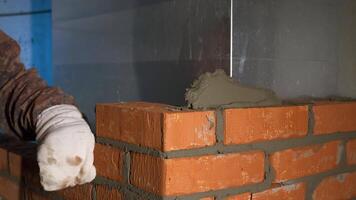 The construction process. Clip. A man in gloves quickly puts a brick on a brick with cement reinforcement. video