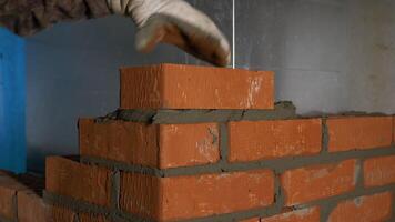 The construction process. Clip. A man in gloves quickly puts a brick on a brick with cement reinforcement. video