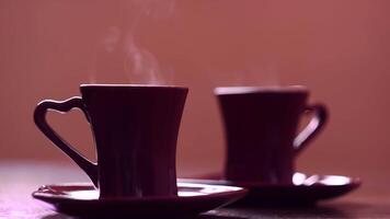 Close-up of steaming hot drink in mugs. Concept. Paired mugs with hot drink stand and evaporate. Beautiful steam comes from steaming mugs with hot coffee video