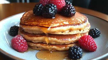 Delicious stack of fluffy pancakes topped with fresh blueberries and syrup served on a blue plate photo