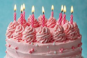 A colorful pink birthday cake with candles and sprinkles set against a bright blue background photo