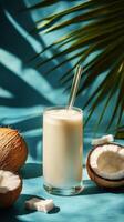 Creamy coconut smoothie topped with crushed nuts served in a tall glass on a blue background photo