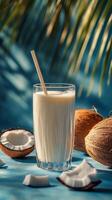 Creamy coconut smoothie topped with crushed nuts served in a tall glass on a blue background photo