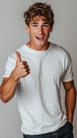 Young man giving a thumbs up gesture while standing against a textured gray wall photo