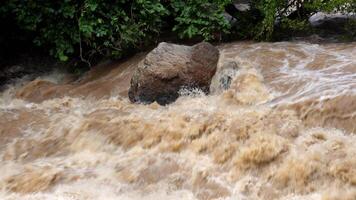 A strong current near a waterfall. Floods flowing in mountain rivers after heavy rains. Flash floods, the effects of global warming and the effects of deforestation. video