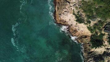 Aerial top view of wild tropical coast of Dominican Republic with rocky cliff and untouched nature.A light breeze rolls onto the shore with turquoise ocean waves.A luxurious landscape for relaxation video