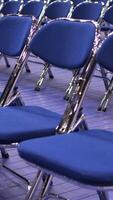 vertical rows of empty blue chairs without spectators before seminar video