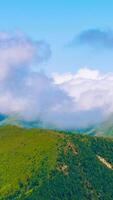 Time lapse vertical of rolling clouds over the forest covered mountains at daytime. video