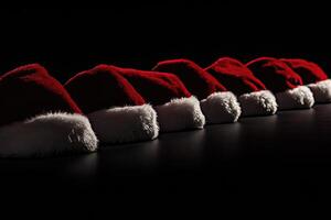 Row of Red and White Santa Hats on a Black Background photo