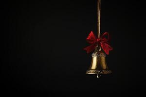 Gold Christmas Bell with Red Bow on Black Background photo