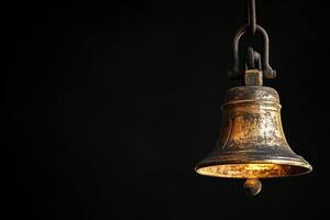 A Large Brass Bell Hanging on a Black Background photo
