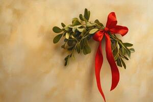 A sprig of mistletoe tied with a red bow on a textured gold background photo