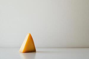 A Triangular Slice of Yellow Cheese on a White Surface photo