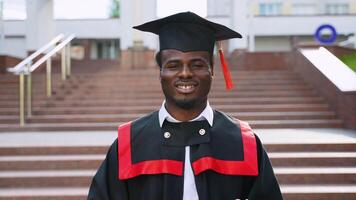 Portrait of smiling student graduate with diploma near university video